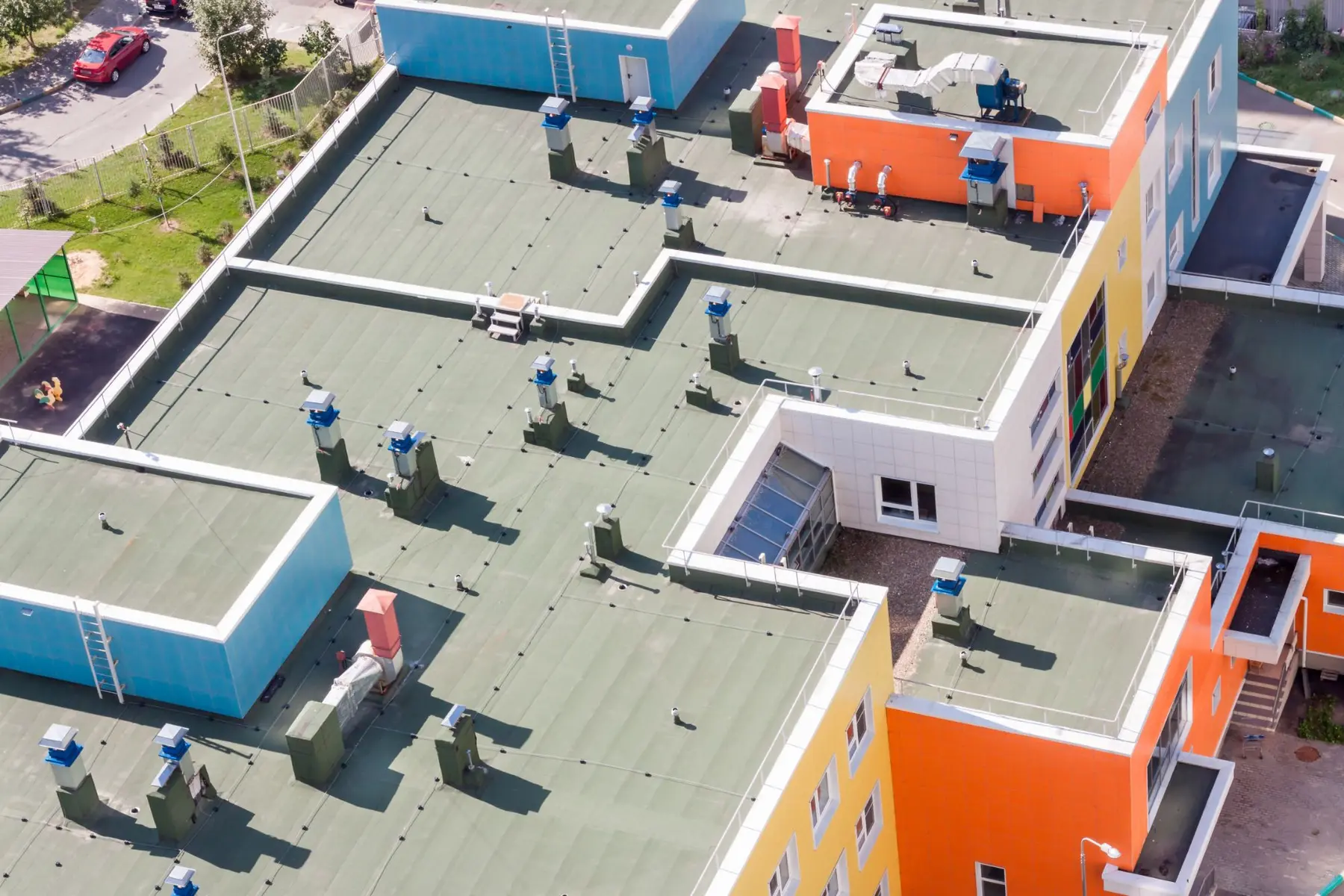 Aerial view of a flat membrane roof with rooftop units, vents, ducting and a skylight