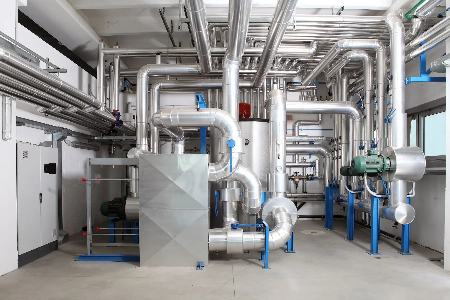 A mechanical room with insulated piping, pumps and an air handler